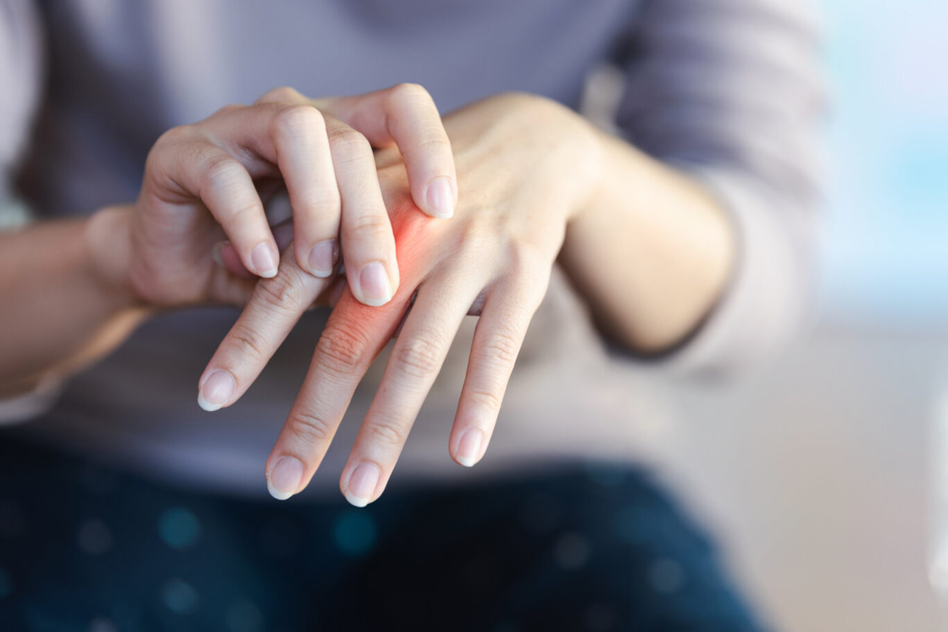 A woman touches a red area on her finger to indicate the pain point.